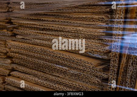 Stapel von welligen Kartonblättern, eingewickelt in Stretchfolie als Hintergrundtextur. Stockfoto