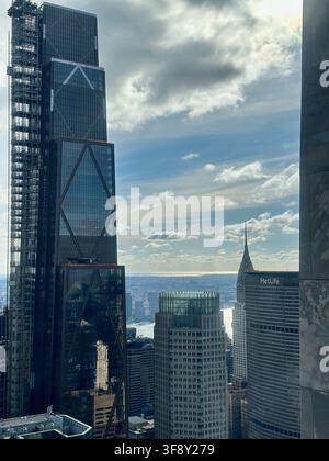 MANHATTAN, USA - 23. NOV, 2024: Sonnenbeschienene Ansicht der Wolkenkratzer von Manhattan, ikonische Bauwerke wie das Empire State Building präsentierend Stockfoto