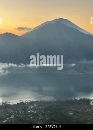Mount Agung bei Sonnenaufgang mit Wolken über seinen Hängen, Bali, Indonesien Stockfoto