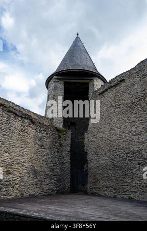Niedrigwinkelaufnahme eines runden Turms mit Schieferdach und rauen Steinmauern bei der Burg Bourscheid in Luxemburg. Stockfoto