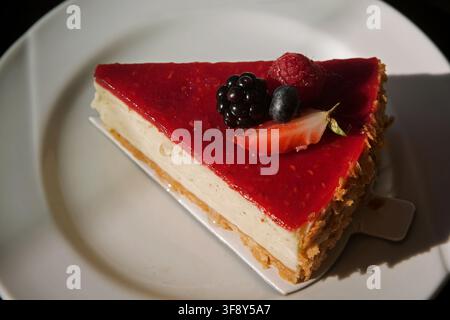 Vanille-Käsekuchen mit Beeren auf einem weißen Teller sonniges Foto. Hochwertiges Foto Stockfoto