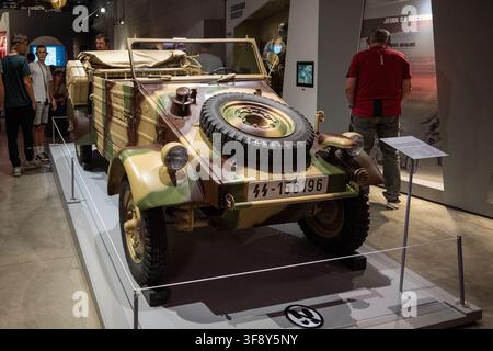 Bastogne, Belgien - 21. Jul. 25: Ein getarntes deutsches Kubelwagen-Militärfahrzeug, das unter Besuchern im Bastogne-Kriegsmuseum ausgestellt ist. Stockfoto