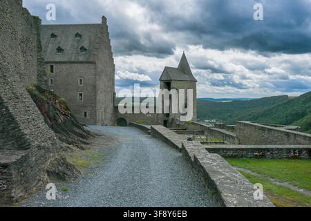 Dramatischer bewölkter Blick auf die Türme der Burg Bourscheid, die Steinmauern und das Tal vom oberen Hof in Luxemburg Stockfoto
