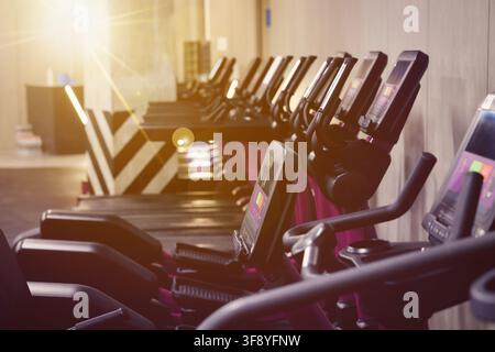 Cardio-Zone mit Fitnessbikes und Laufbändern in einem sonnendurchfluteten Fitnessstudio, selektive Fokussierung Stockfoto