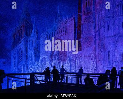 Leipzig, Deutschland - 12. Jul 25: Silhouettierte Besucher betrachten eine blau beleuchtete gotische Kathedralpanorama mit Rosettenfenster und Turmdetails im Inneren von Leipzig Stockfoto