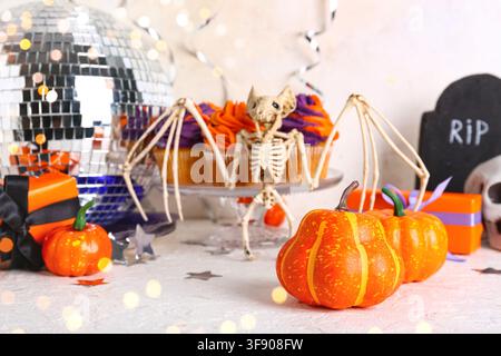 Halloween-Party-Dekorationen mit Fledermaus-Skelett, Kürbissen, Cupcakes und Diskokugel auf einem festlichen Tisch Stockfoto