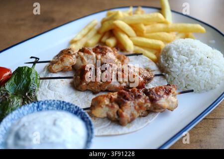 Gegrillte Hähnchenspieße mit Reis und Pommes frites Stockfoto