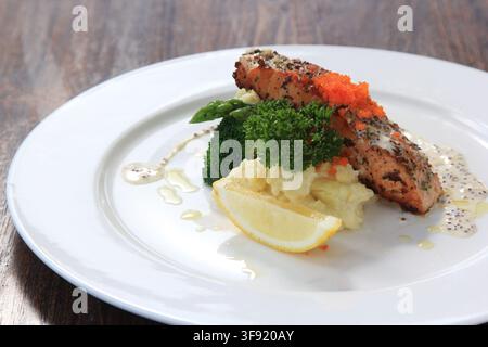 Gegrilltes Lachssteak mit Kartoffelpüree, Brokkoli und Zitronenscheibe auf einem weißen Teller, Nahaufnahme des Essens. Stockfoto
