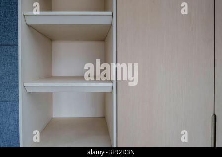 Sauberer minimalistischer Nahaufnahme-Aufnahme eines maßgefertigten Einbaukleiderschranks mit offenen Ablagefächern und glatten Schranktüren. Das helle natürliche Holz. Stockfoto