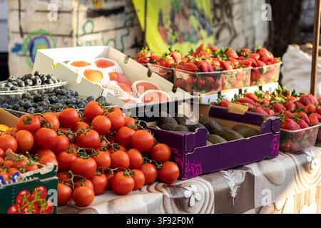 Farbige Bio-Produkte, die an einem sonnenbeschienenen Lebensmittelladen präsentiert werden und saisonale Früchte und Gemüse hervorheben, die natürliche Zutaten für das Kochen betonen Stockfoto