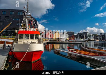 Farbenfrohe Gebäude und Boote im Hafen von Troms, Norwegen, unter blauem Himmel Stockfoto