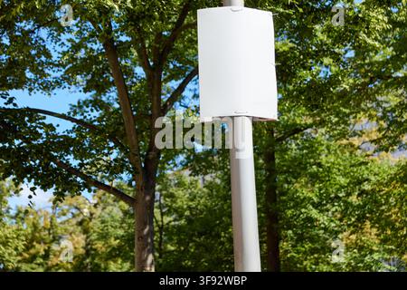 Leere weiße Wahlplakatvorlage, die hoch an einer Laternenpfähle im Sommer hängt und als Design-Mockup dient Stockfoto