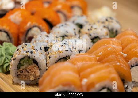 Leckere Auswahl an handgerolltem Sushi, serviert auf einem Holzbrett mit Ingwer und Wasabi, das erstklassige Zutaten für ein feines Esserlebnis widerspiegelt Stockfoto