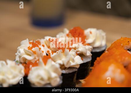 Appetitliche Sushi-Rollen, garniert mit reichhaltigem Frischkäse und herzhaftem Tobiko-Fischrogen, präsentiert in einer Nahaufnahme-Makroansicht, ideal für kommerzielle Lebensmittelfotos Stockfoto