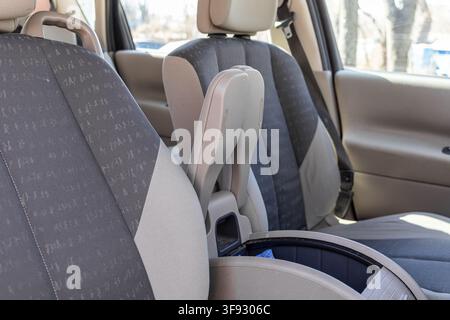 Nahaufnahme einer gefalteten Armlehne zwischen grauen gemusterten Sitzen, die funktionales Innendesign, praktischen Stauraum und ergonomische Fahrzeuggestaltung hervorhebt Stockfoto