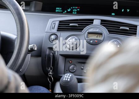 Ein modernes Armaturenbrett eines Autos mit wesentlichen Bedienelementen wie dem Schalthebel, dem Lenkrad und dem digitalen Klimadisplay, das eine klare Sicht bietet für dai Stockfoto