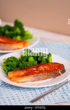 Gegrillte Lachsfilets serviert mit frischem Brokkoli auf einem weißen Teller, repräsentierend gesunde Ernährung, ausgewogene Ernährung, proteinreiche Mahlzeiten und ein gesundes Stockfoto