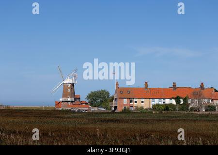 Windmühle von Cley next the Sea und farbenfrohe Reihenhäuser, gesehen über das Schilfrohr Stockfoto