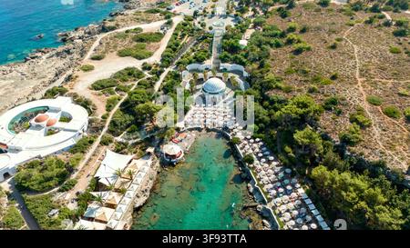 Luftaufnahme von Sonnenliegen, einer türkisfarbenen Bucht, einem Kuppelpavillon und pinienbewachsenen Hügeln, Kallithea Springs, Rhodos, Griechenland. Stockfoto