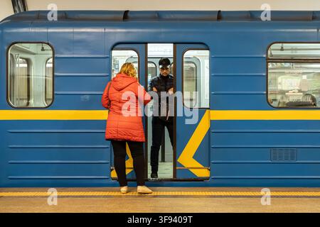 Kiew, Ukraine – 15. März 2026: Zwei Personen stehen am offenen Eingang eines farbenfrohen Verkehrsmittels in einer unterirdischen Großstadtstation, krank Stockfoto