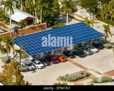 In die städtische Infrastruktur integrierte Solarstromerzeugung. Photovoltaikpaneele als Schattendach über dem Parkplatz mit geparkten Autos installiert Stockfoto