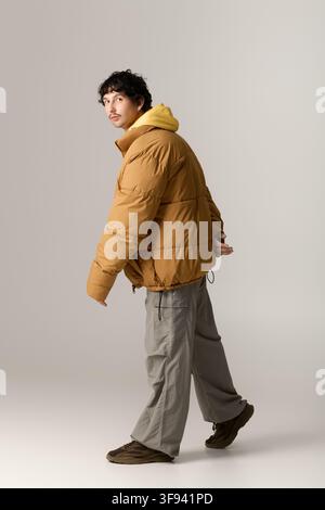 Ein junger Mann präsentiert seinen modischen Stil in einem warmen, kuscheligen Outfit, während er selbstbewusst drinnen posiert. Stockfoto