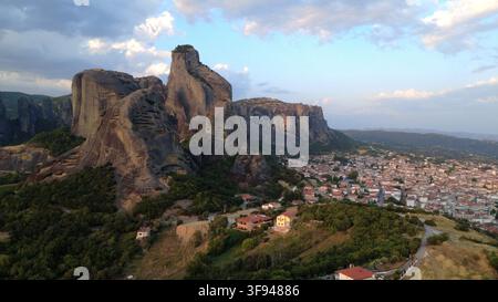 Luftbild der dramatischen Meteora-Felsformationen, die zur golden Stunde über der Stadt Kalambaka aufragen, mit üppigen grünen Wäldern und einer weitläufigen Stadtlandschaft Stockfoto