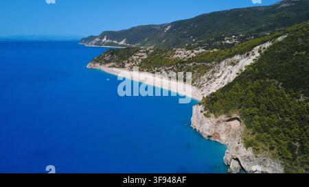 Atemberaubende Luftaufnahme einer abgelegenen Strandbucht mit türkisfarbenem Wasser, dramatischen Kalksteinklippen und üppig grünen Bergen entlang einer Mittelmeerküste Stockfoto