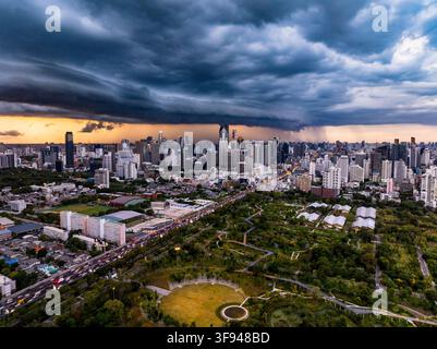 Bangkok, Thailand - 20. Juni 2024: Luftaufnahme der Skyline von Bangkok und des Benjakitti-Parks in Khlong Toei unter einer dramatischen dunklen Gewitterwolke bei Sonnenuntergang, f Stockfoto