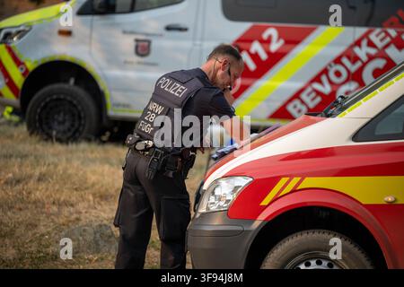 14. August 2026, Nordrhein-Westfalen, Hürtgenwald: Ein Polizeibeamter überprüft Dokumente, während er den Brand im Hürtgenwald bekämpft. Foto: Harald Tittel/dpa Stockfoto