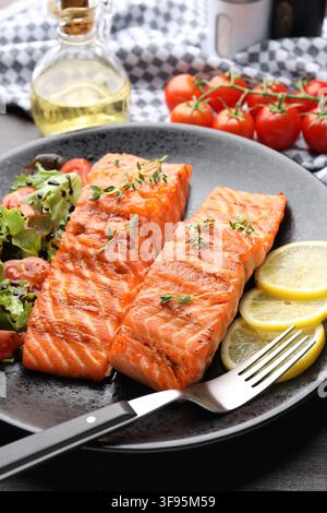 Stücke gegrillten Lachses, serviert mit Salat auf dem Tisch, Nahaufnahme Stockfoto