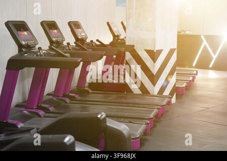 Cardio-Zone mit Laufbändern in einem sonnendurchfluteten Fitnessstudio Stockfoto