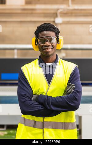 Afrikanischer Arbeiter mit Sicherheitsausrüstung in einer Sägerei Stockfoto