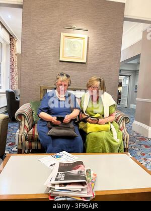 Zwei alte Damen mit Mobiltelefonen im The White Lion Hotel, Aldeburgh Suffolk P15 5BJ Vereinigtes Königreich Stockfoto