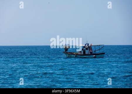 Calp, Spanien - 11. Juli 2027: Blick auf ein kleines Fischerboot, das auf dem ruhigen blauen Meer unter einem klaren Himmel schwebt. Stockfoto