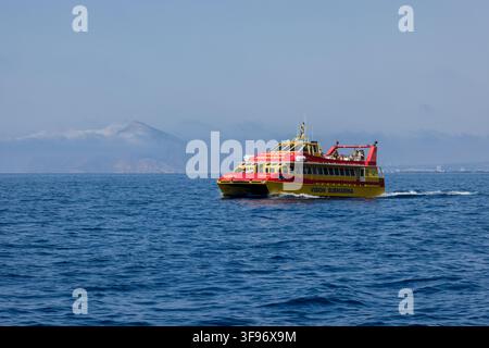 Calp, Comunidad Valenciana, Spanien - 11. Juli 2027: Blick auf ein gelbes und rotes Glasbodenboot, das auf dem Mittelmeer mit dem Penon de Ifach kreuzt Stockfoto
