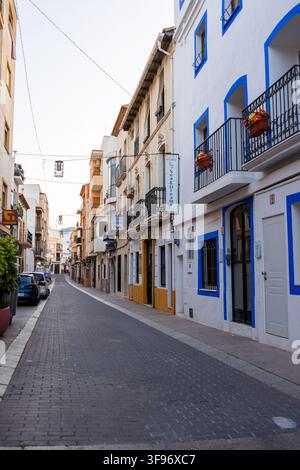 Calp, Spanien - 11. Juli 2027: Blick auf die schmale Kopfsteinpflasterstraße in der historischen Altstadt von Calp, mit traditionellen weißen Gebäuden und blauen Wi Stockfoto