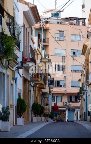 Calp, Spanien - 11. Juli 2027: Blick auf die historische Altstadtstraße mit traditionellen Gebäuden, Balkonen und Menschen, die den schmalen Weg in Ca entlanggehen Stockfoto