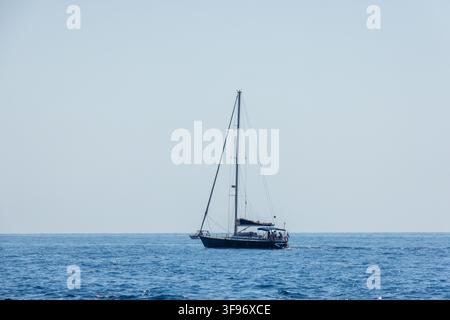 Calp, Comunidad Valenciana, Spanien - 11. Juli 2027: Blick auf ein Segelboot, das unter einem klaren Himmel auf dem ruhigen blauen Mittelmeer segelt. Stockfoto