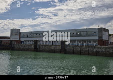 Großes industrielles Hafenlager und Steinquai entlang der Uferpromenade im Hafen von Holyhead, Anglesey, Nordwales, UK. Stockfoto