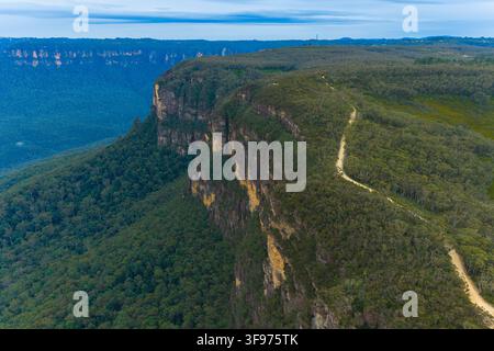 Drohnen-Luftbild der Felswand und eines Feldweges, der entlang der Kammlinie des Jamison Valley in den Blue Mountains Nationalpark verläuft Stockfoto
