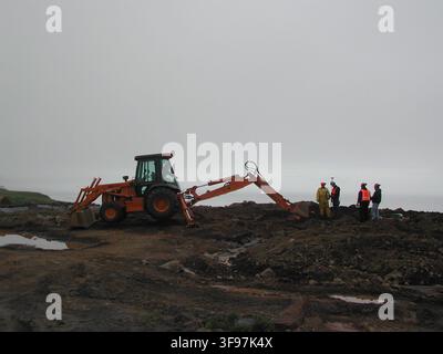 Mitarbeiter der St. George Chadux Corporation und Subunternehmer führen Bodenprobenentnahmen am Standort des Enhanced Thermal Conduction Soil Remediation Systems auf St. George Island, Alaska, durch, im Rahmen des Pribilof Islands Restoration Projects, wobei Barry Lestenkof einen Case 590 Super L Radlader bedient, Brian Brown als Umweltechniker assistiert, John Fox Probenstandorte mit einem Trimble RTk 5700 GPS vermisst und Anthony Lekanof und Andronik Kashevarof die Baustellensicherheit und Projektleitung überwachen. Stockfoto