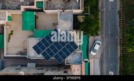 Luftbild von Solarpanelen, die auf einem Wohnhausdach montiert sind, mit einem weißen Auto, das unten auf der Straße in Lahore, Punjab, Pakistan, geparkt ist. Stockfoto