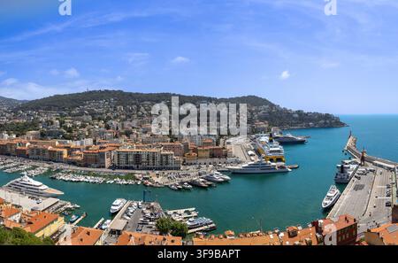 Luftaufnahme des Hafens von Nizza mit Luxus-Yachten, Fährschiffen und historischen Gebäuden entlang der Uferpromenade unter einem klaren blauen Himmel in Nizza, Provence-Alpes Stockfoto