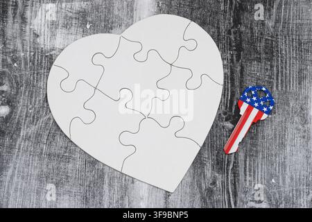 Leeres weißes Puzzleherz mit USA-Flaggen-Schlüssel auf verwittertem Holz für Patriotismus und den amerikanischen Traum Stockfoto