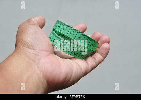 Hand, die ein grünes Maßband hält Stockfoto