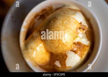 Vanilleeis mit Kaffee in einer weißen Keramiktasse, Nahaufnahme eines Desserts mit cremigen Spiralen Stockfoto