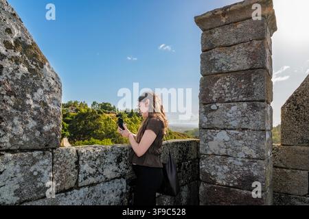Junge Frau erstellt Reiseinhalte an einer alten Steinmauer Stockfoto