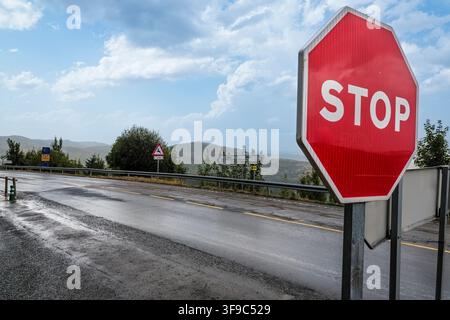 Stoppschild, das auf einer nassen Bergstraße steht Stockfoto