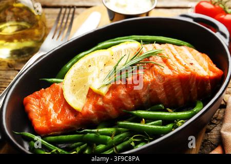 Köstliches gegrilltes Lachsfilet mit grünen Bohnen, Zitrone und Rosmarin, serviert auf dem Tisch, Nahaufnahme Stockfoto